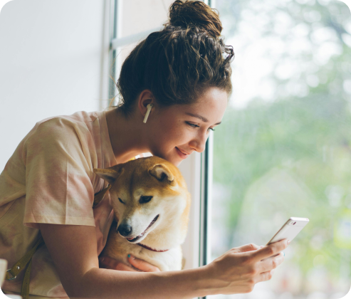Woman holding her dog while checking her phone