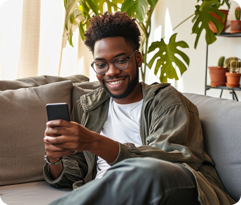 Man smiling while using his phone on the couch